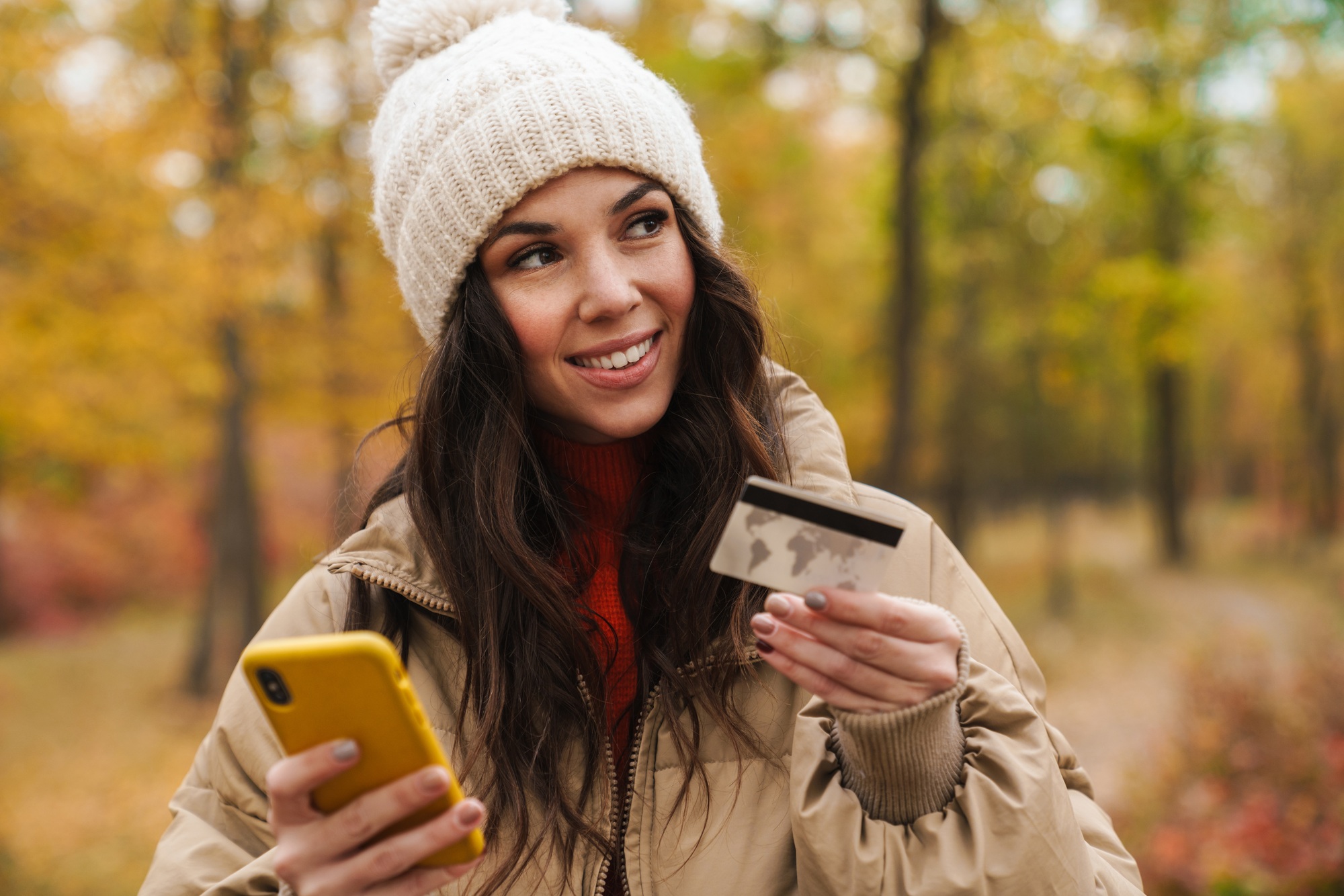 Nice smiling woman holding credit card and cellphone