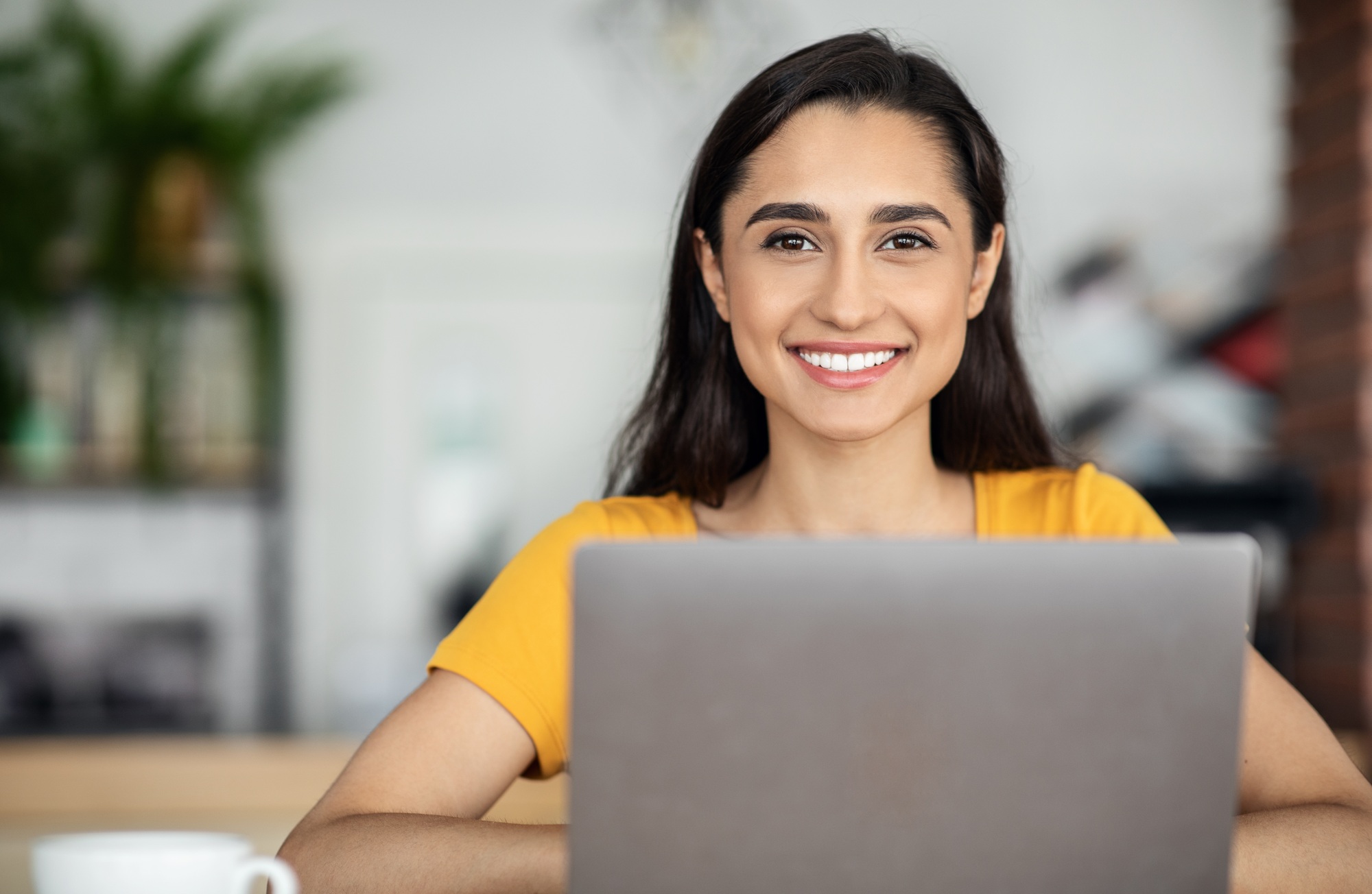 Pretty smiling arab girl using laptop at cafe