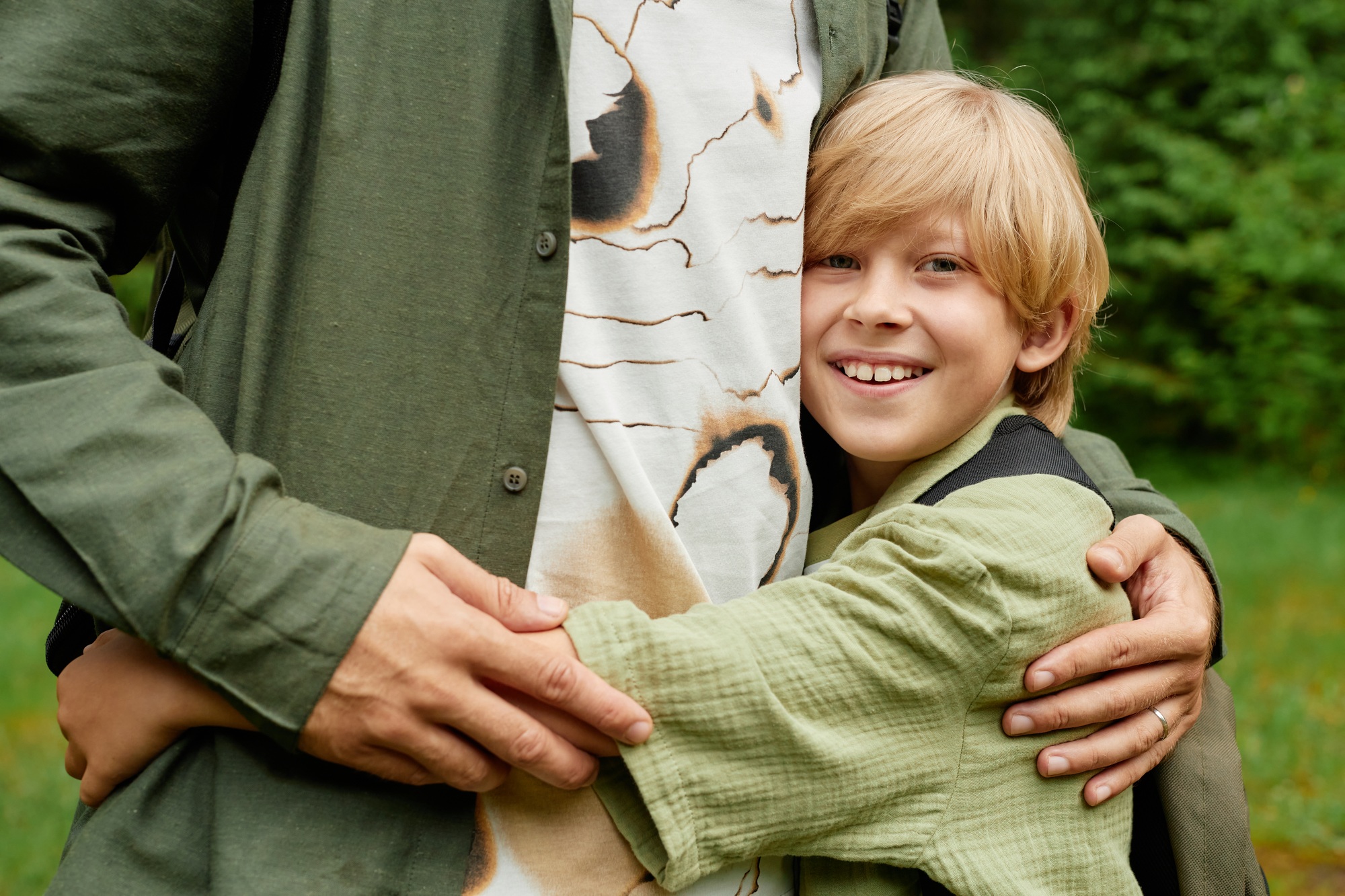 Smiling Child Embracing Adult in Outdoor Setting